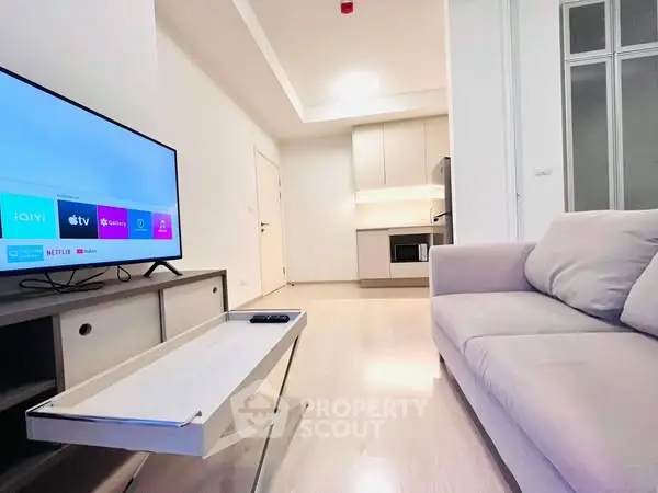 Modern living room with sleek TV setup and cozy sofa in bright apartment.