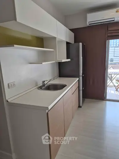 Modern kitchen with sleek cabinetry and stainless steel fridge in a bright apartment.