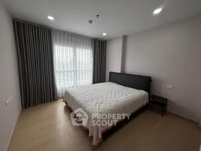 Spacious bedroom with large window and modern decor in a stylish apartment.