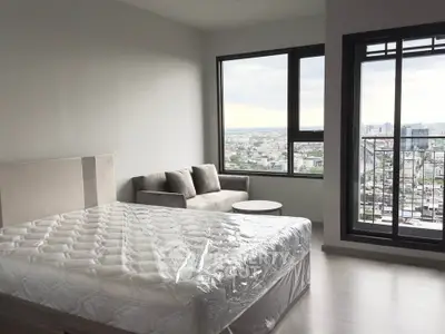 Modern bedroom with city view and balcony access in high-rise apartment