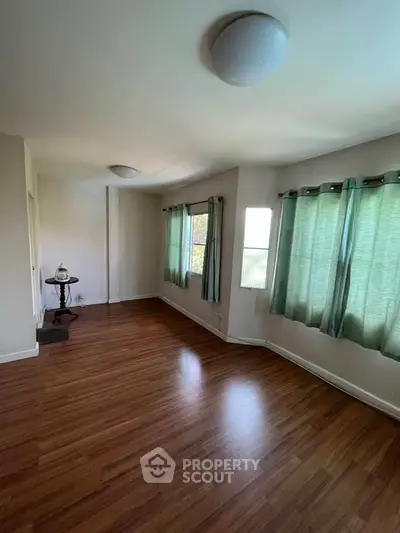 Spacious living room with wooden flooring and large windows for natural light.