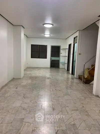 Spacious interior with tiled flooring and staircase, ideal for customization