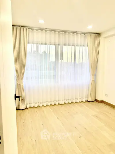 Bright empty room with large window and elegant curtains, perfect for customization.