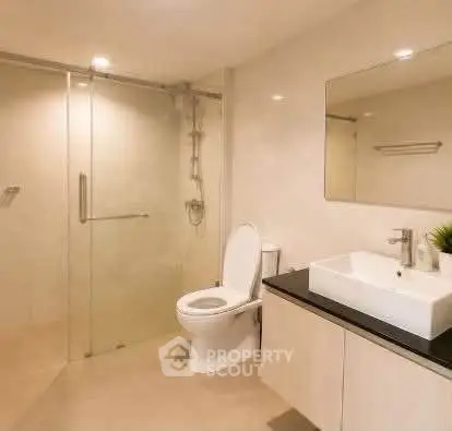 Modern bathroom with glass shower and sleek vanity in a contemporary home.