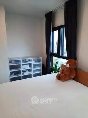 Cozy bedroom with plush teddy bear and city view window, perfect for relaxation.