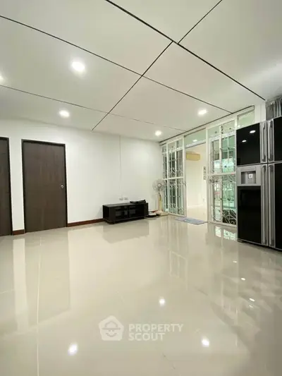 Spacious modern living room with glossy tiled floors and large windows.