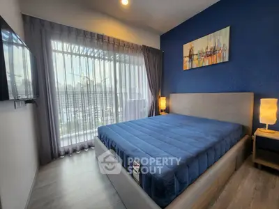 Modern bedroom with blue accent wall and large window in stylish apartment