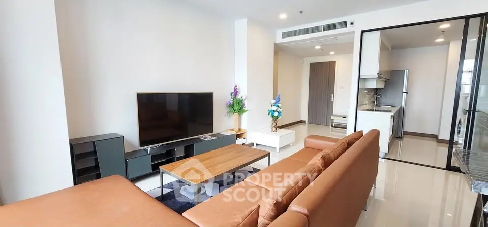 Spacious modern living room with sleek furniture and open kitchen layout in a contemporary apartment.