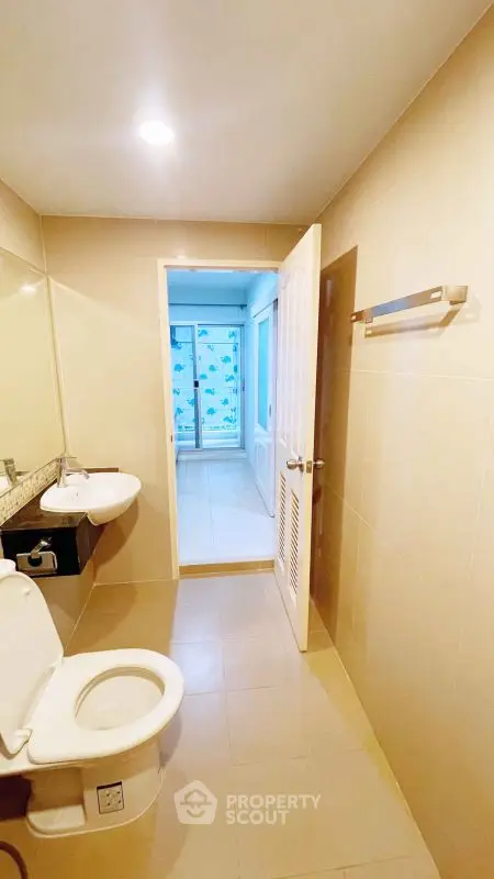 Spacious bathroom with modern fixtures and open doorway to bright room.