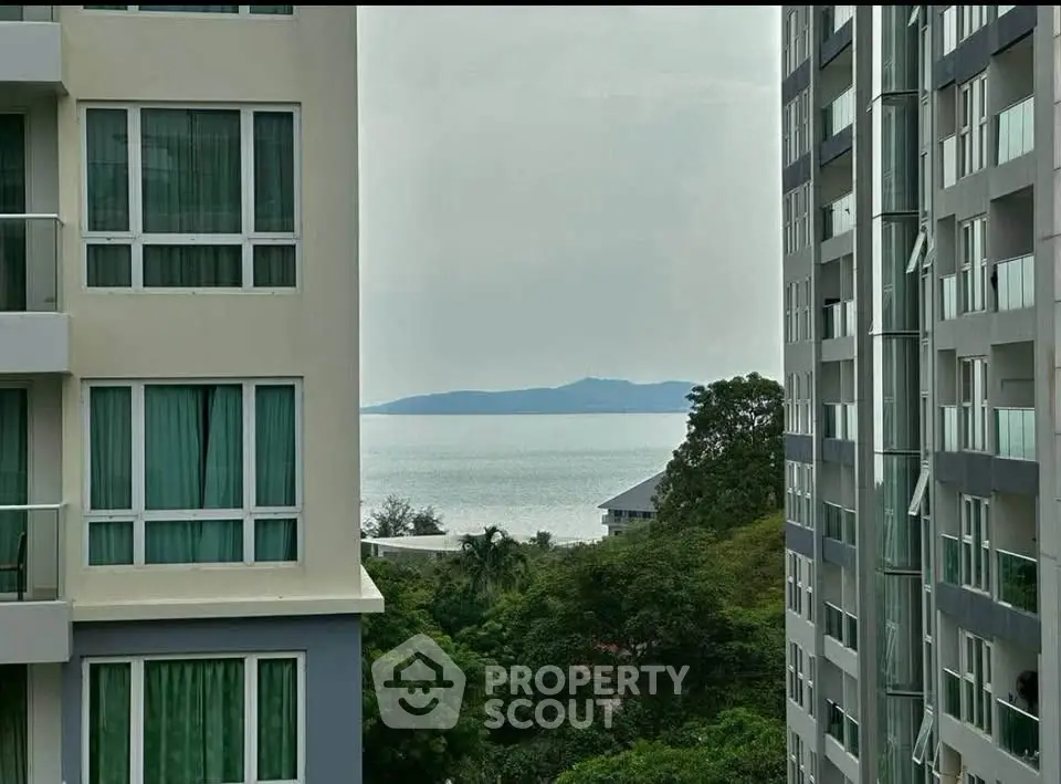 Stunning ocean view from high-rise apartment with lush greenery and modern architecture.
