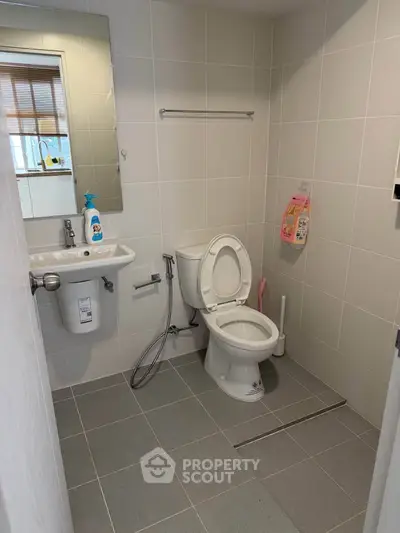 Modern bathroom with sleek fixtures and tiled walls, featuring a toilet and sink.