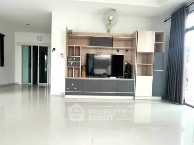 Spacious modern living room with sleek entertainment center and large windows for natural light.