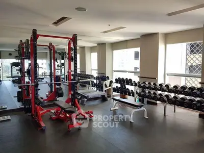 Spacious gym with modern equipment and large windows in a residential building.