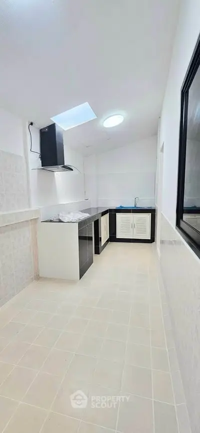 Spacious kitchen with modern design and ample natural light, featuring sleek cabinetry and a stylish range hood.