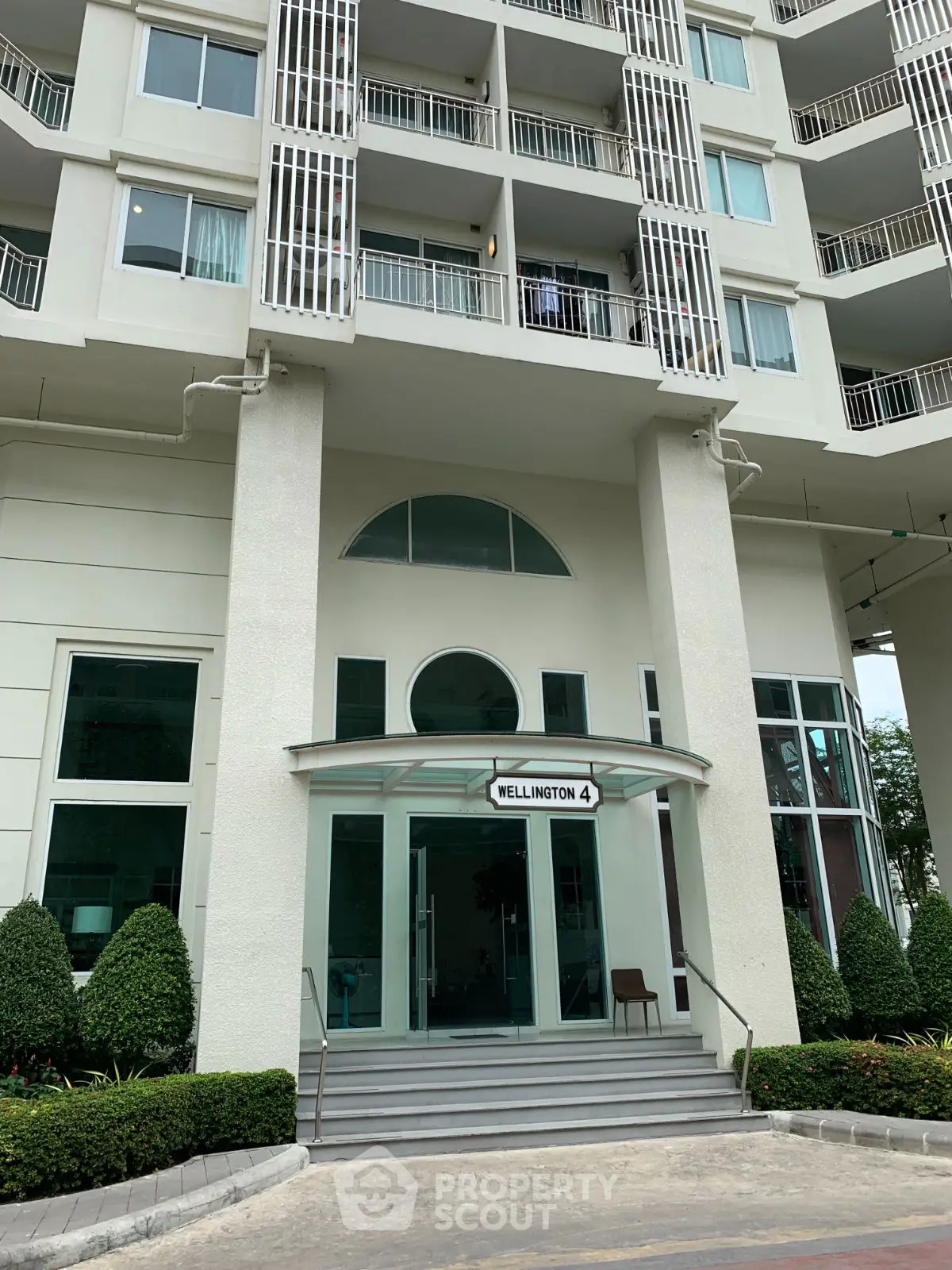 Elegant apartment building entrance with modern design and lush landscaping