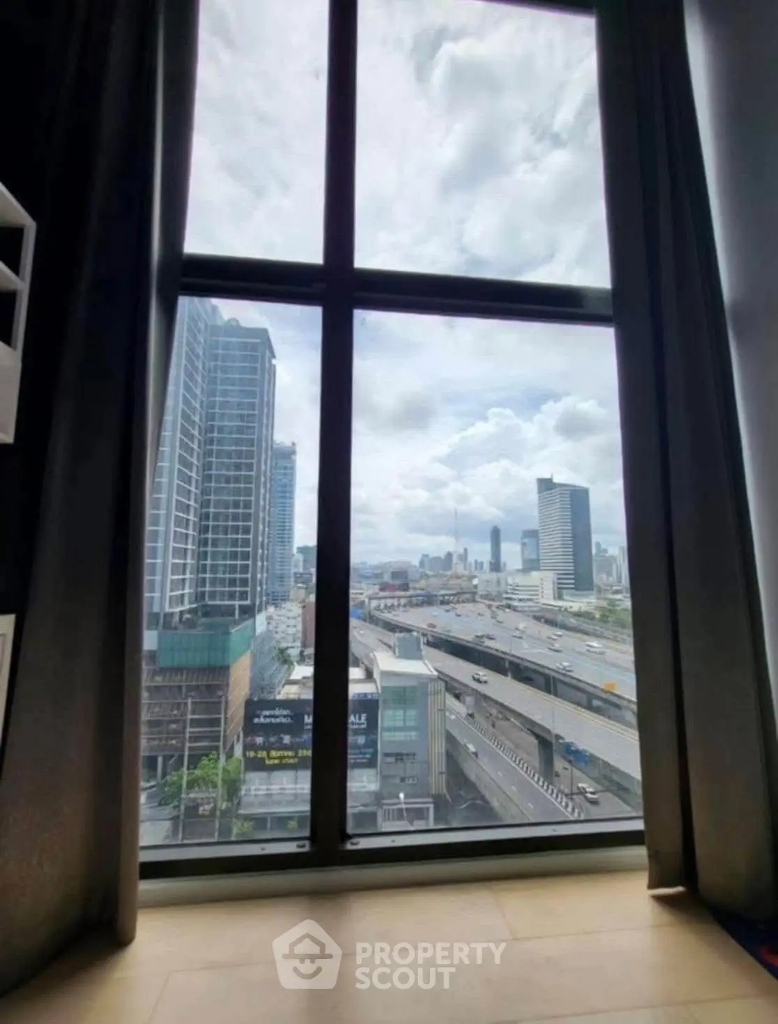 Stunning cityscape view from high-rise apartment window with expansive skyline and highway.