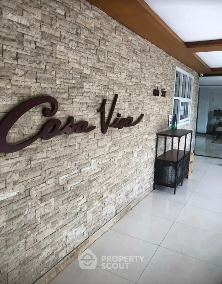 Stylish building entrance with modern stone wall and sleek decor.