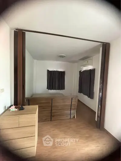 Cozy bedroom with wooden flooring and modern furnishings in a minimalist style.