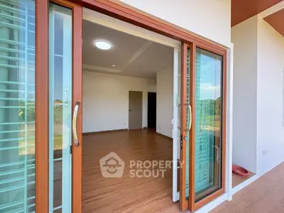 Modern sliding glass doors open to a spacious wooden-floored interior with natural light.