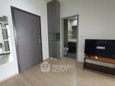 Modern apartment interior with TV and bathroom view, showcasing sleek design and functionality.