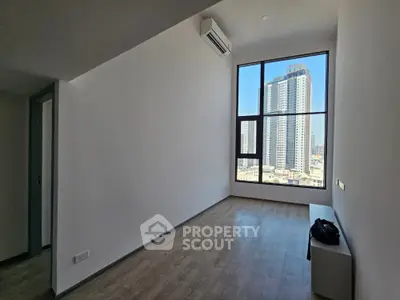 Spacious and sunlit living room with large windows offering an expansive city view, featuring high ceilings and modern wooden flooring, ideal for personalizing your dream urban space.