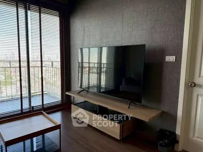 Modern living room with large TV and balcony view in stylish apartment.