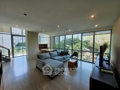 Spacious modern living room with large windows and city view, featuring stylish furniture and natural light.
