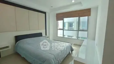 Spacious bedroom with large window and modern decor in a bright apartment.