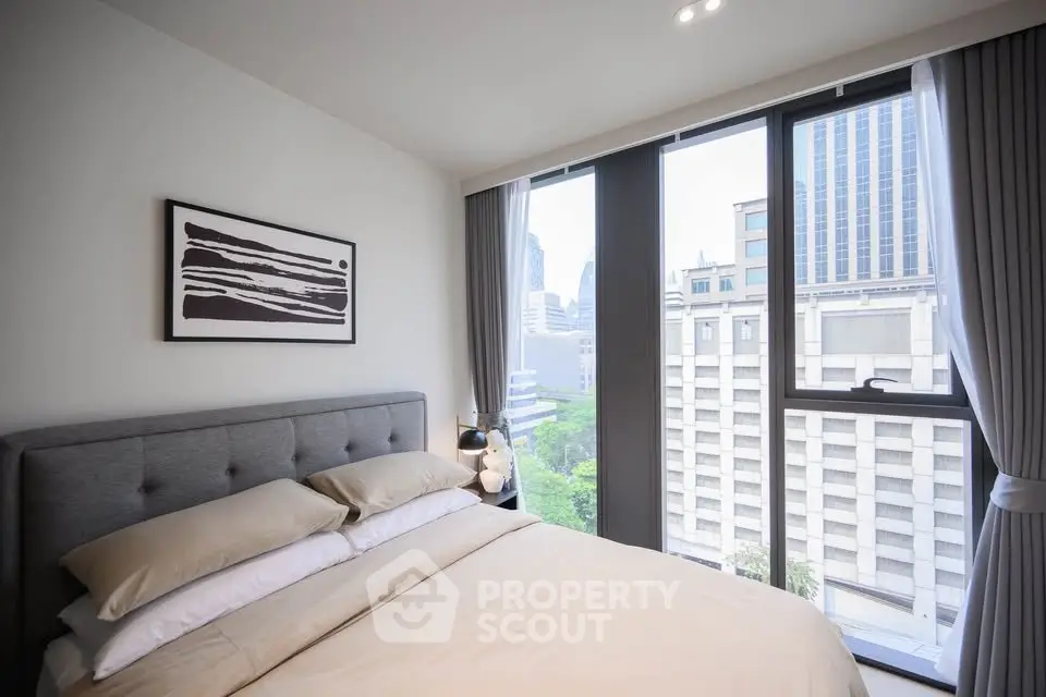 Modern bedroom with large windows offering stunning city views in a high-rise apartment.