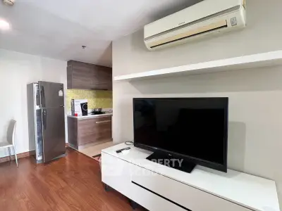 Modern living room with sleek TV unit and open kitchen layout in stylish apartment.