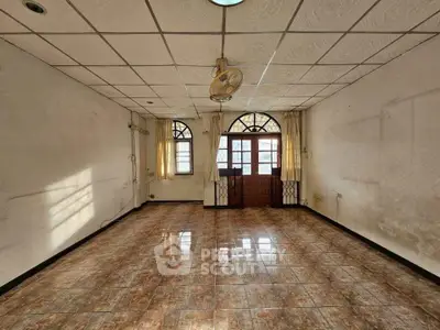Spacious empty room with tiled floor and large windows, ideal for customization.