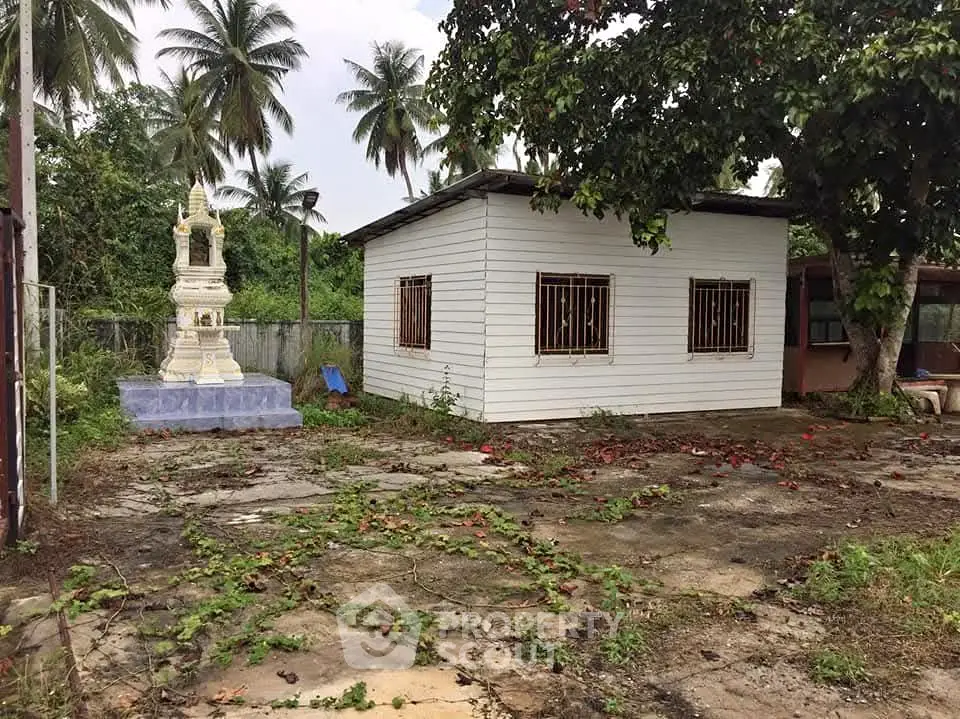 Charming rustic house with lush greenery and unique outdoor shrine, perfect for serene living.