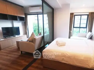 Modern studio apartment with cozy living area and large windows offering natural light.