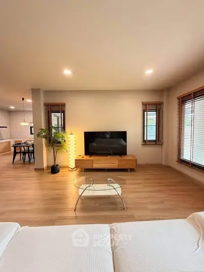 Spacious modern living room with wooden floors, stylish furniture, and natural light.