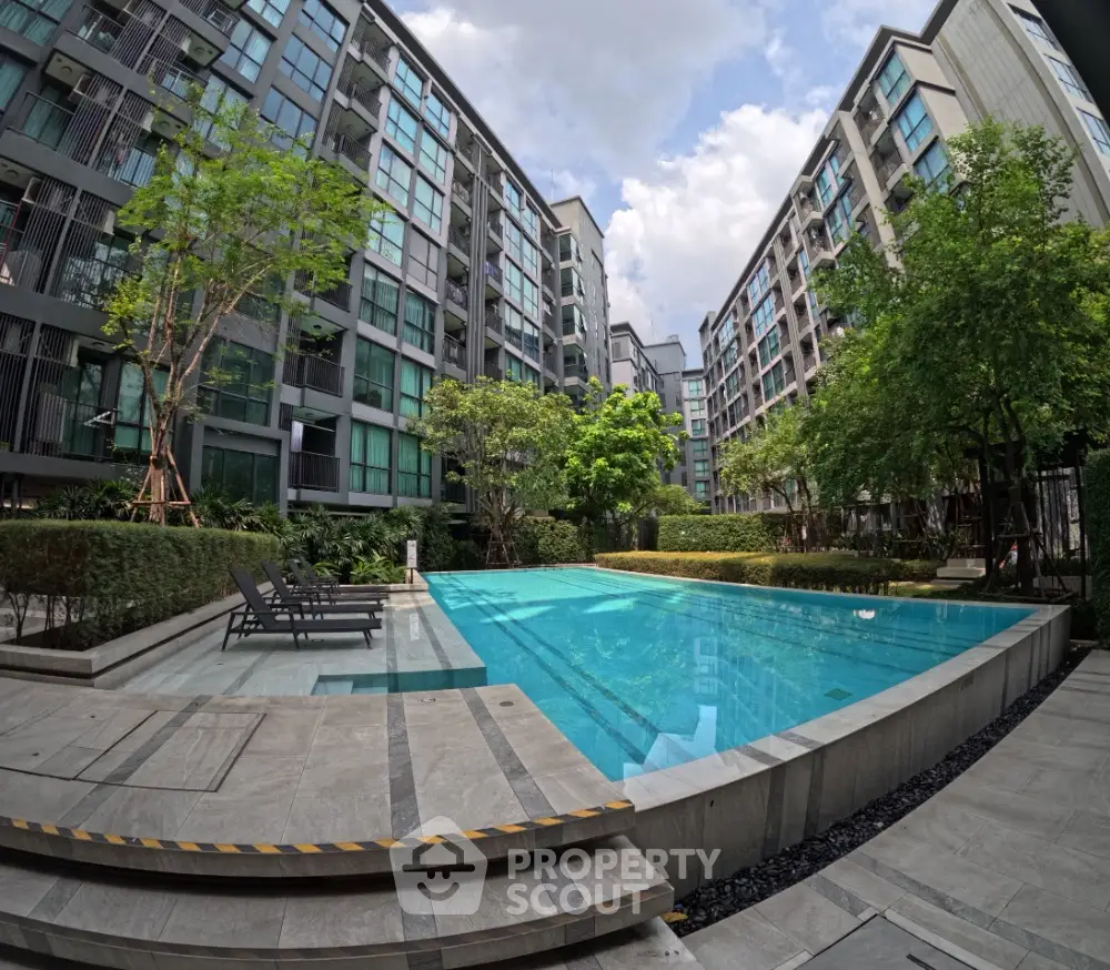 Luxurious modern apartment complex with stunning pool and lush greenery, perfect for urban living.