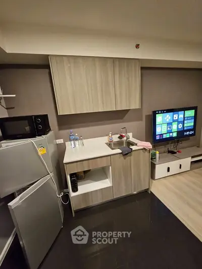 Modern kitchen with sleek cabinetry and open layout, featuring a TV and appliances for a cozy living space.
