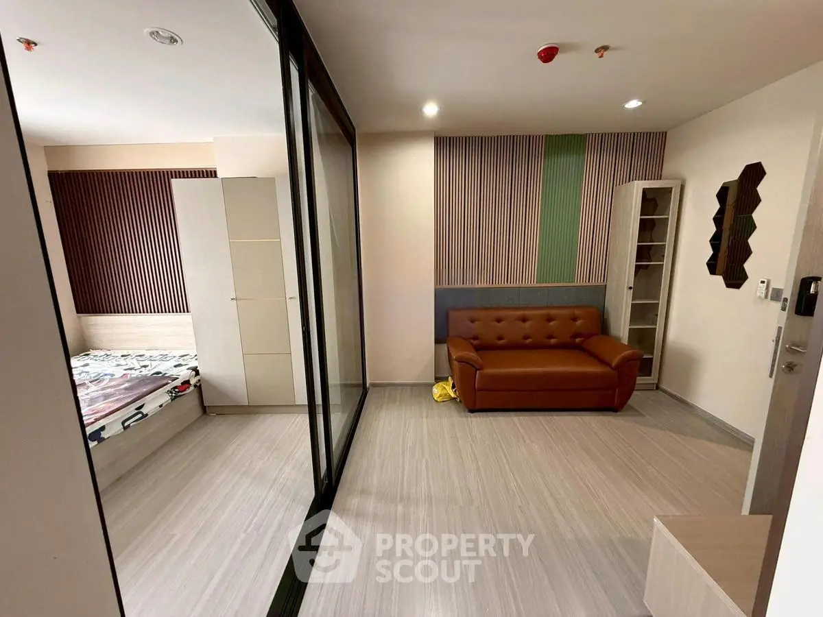 Modern apartment interior with cozy living room and adjacent bedroom, featuring stylish decor and sleek flooring.