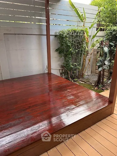 Beautifully polished wooden deck with lush greenery, perfect for outdoor relaxation.