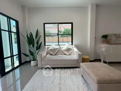 Modern living room with plush sofa, large window, and elegant decor in a bright, airy space.