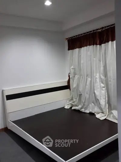 Spacious bedroom with modern bed frame and elegant curtains, perfect for a cozy retreat.