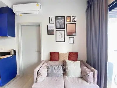Cozy living room with modern decor and wall art, featuring a comfortable sofa and stylish blue kitchen corner.