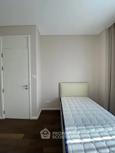 Minimalist bedroom with single bed and hardwood floor, perfect for cozy living.