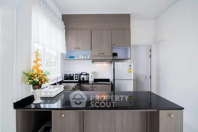 Modern kitchen with sleek cabinetry and stainless steel appliances, featuring a stylish black countertop and bright decor.