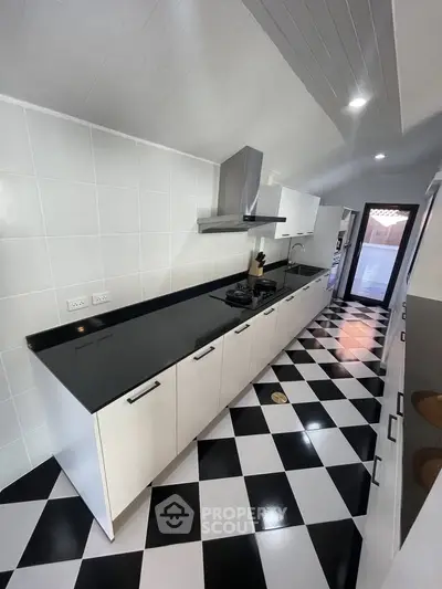 Modern kitchen with sleek black and white checkered flooring and contemporary cabinetry