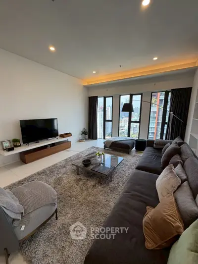 Spacious modern living room with large windows and city view, featuring cozy seating and stylish decor.