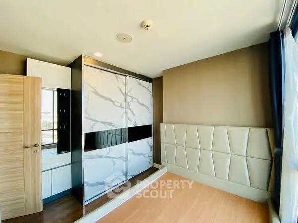 Modern bedroom with stylish wardrobe and large window for natural light.