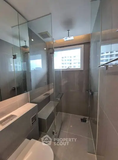 Modern bathroom with glass shower and sleek fixtures in contemporary apartment.