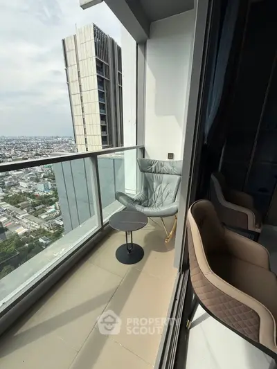 Modern high-rise balcony with city view, featuring stylish seating and glass railing.