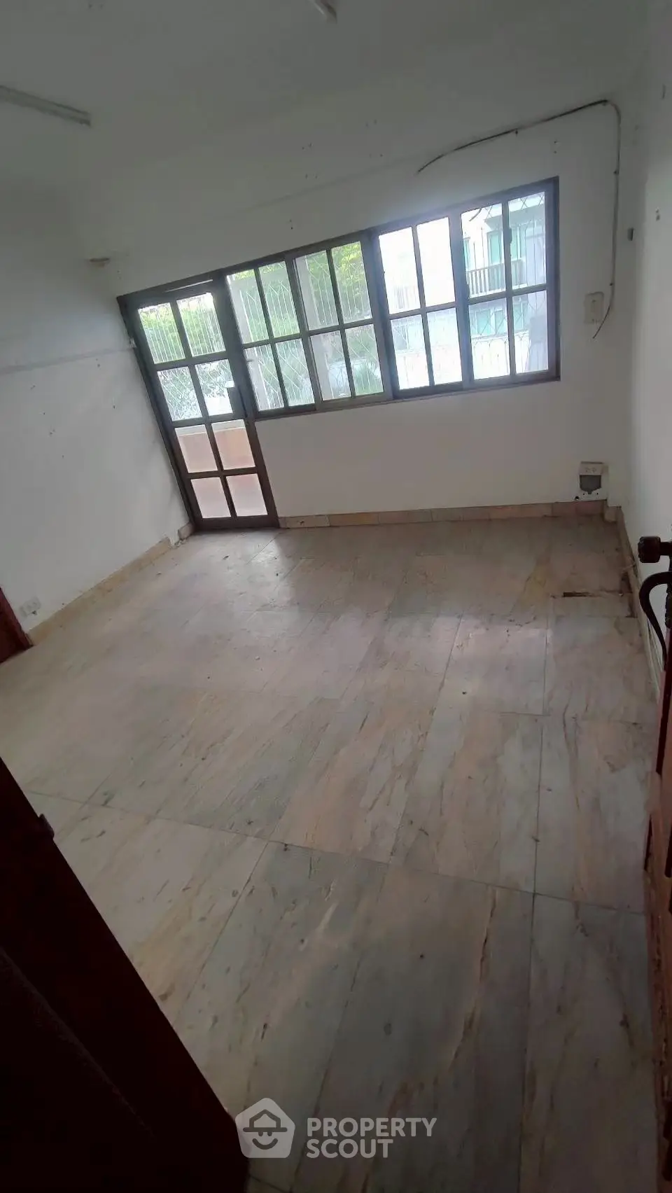 Spacious empty room with large windows and marble flooring, ideal for customization.