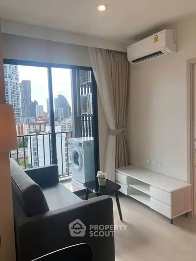 Modern living room with balcony view, air conditioning, and washing machine in urban apartment.